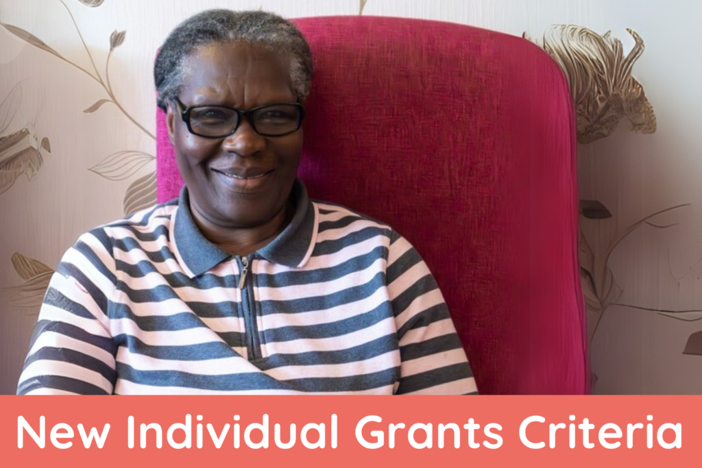 Smiling older woman in glasses and a striped shirt sitting in a red chair, with text at the bottom that reads “New Individual Grants Criteria.” Ask ChatGPT